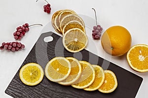 Sliced slices of fresh orange on a cutting board. Half and whole orange. Bunches of frozen red berries