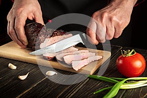 Sliced smoked meat. Cooking juicy beef steak by chef hands on dark background with copy space for text menu or recipe