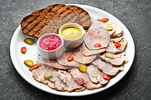 Sliced smoked meat and salami with sauce on a white plate.