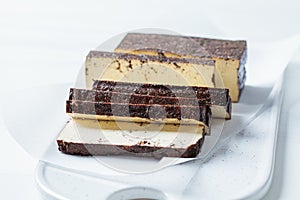 Sliced smoked tofu on white board, white background. Vegan food concept