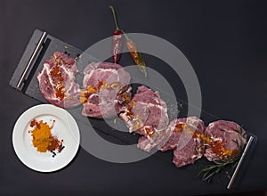 Sliced and spiced pork meat for barbecue on black background