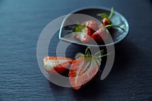 Sliced strawberries on black plate