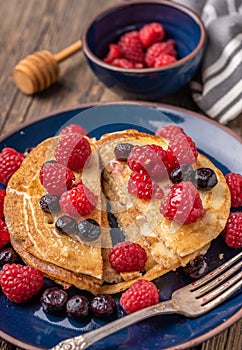 Sliced sweet homemade pancakes with raspberries and blueberries on blue plate