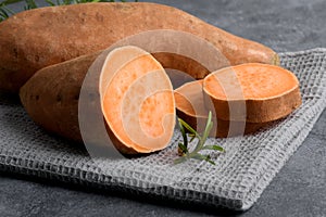 Sliced sweet potato on wooden board background, close up. Raw sweet potatoes or batatas
