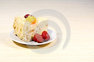 Sliced tasty cake with straberry and peach on wooden background