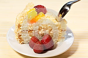 Sliced tasty cake with straberry and peach on wooden background