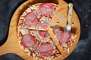 Sliced tasty pizza on chopping board, top view.