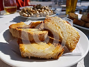 Sliced toasted bread with butter, with cooked snails in the background