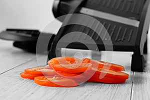 Sliced tomato with mandoline on a grey wood kitchen worktop