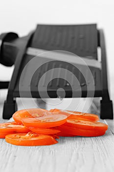 Sliced tomato with mandoline on a grey wood kitchen worktop