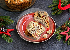 Sliced traditional Scottish Christmas Dundee fruit cake with dried fruit mix, garnished with peeled almonds on a red plate against