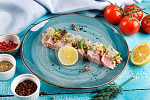 Sliced tuna steak with sesame seeds on a blue plate