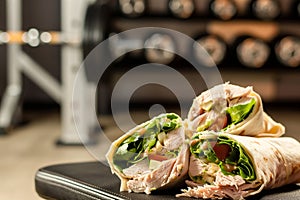 sliced turkey wrap in front of a blurry weight bench