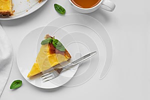 Sliced upside down pineapple cake decorated green leaves with cup of tea on white table. Summer tropical dessert. Top view. Copy