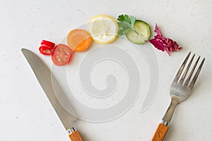 Sliced vegetables and fruits with knife and fork on light background, healthy diet concept