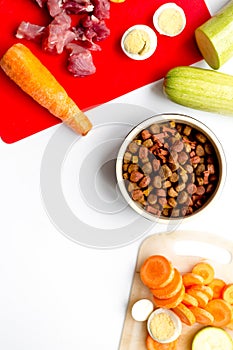 Sliced vegetables and petfood on kitchen table background top view mock up