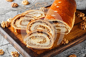 Sliced walnut roll made from yeast dough close-up on a wooden board. Horizontal