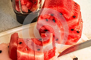 Sliced watermelon, knife and part of mixer on kitchen board