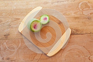 Sliced watermelon radish on a bamboo cutting board, old wood background