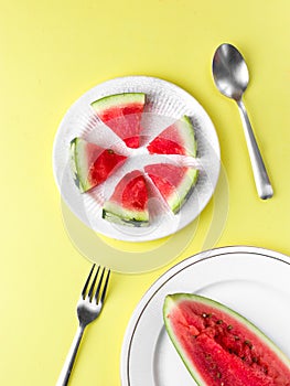 Sliced Watermelon on white plate with spoon and fork stock photo with bright background.