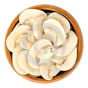 Sliced white champignon mushrooms in wooden bowl