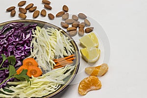 Sliced white and red cabbage in plate, citrus fruits and nuts