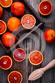 Sliced and whole ripe juicy blood oranges and grapefruit in the box on wooden background.