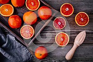 Sliced and whole ripe juicy blood oranges and grapefruit in the box on wooden background.