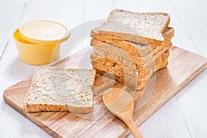 Sliced whole wheat bread with butter on white wooden table