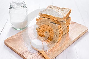 Sliced whole wheat bread with sugar on white wooden table