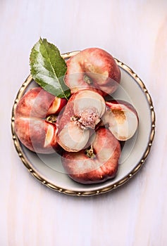 Sliced â€‹â€‹fresh peach with leaf in plate on a white wooden background, top view