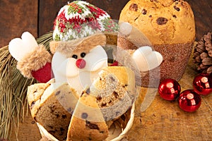 Sliced â€‹â€‹panettone in a Santa Claus basket and Christmas balls on the rustic wooden table with black background, selective