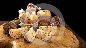 Sliced â€‹â€‹panettone in a Santa Claus basket and Christmas balls on the rustic wooden table with black background, selective