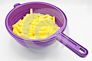Sliced â€‹â€‹potatoes in purple plastic colander