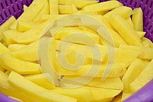 Sliced â€‹â€‹potatoes in purple plastic colander