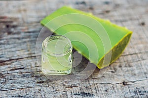 Slices of a aloe vera leaf and a bottle with transparent gel for
