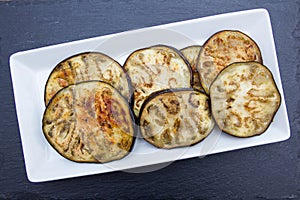 Slices of aubergine on slate from above