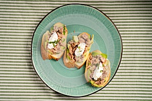 Slices of baguette with fresh tuna, cream cheese and chopped onion chives on marble board. Christmas themed dinner table