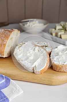 Slices of baguette with tofu cream cheese on white wooden table