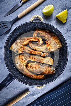 Slices of baked carp fish in frying pan, a traditional Polish Christmas dish