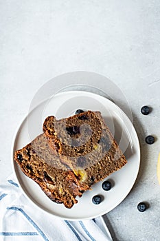 Slices of banana bread with blueberries served on a plate on a gray background. Top view