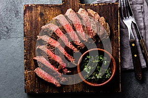 Slices of beef medium rare steak on wooden board, glass of red wine