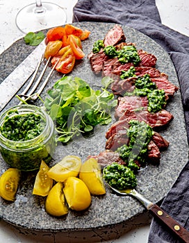 Slices of beef steak with chimmichuri sauce on gray stone plate