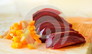 Slices of boiled red beat and carrots on a wooden board