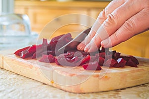 Slices of boiled red beat on a wooden board and a hand