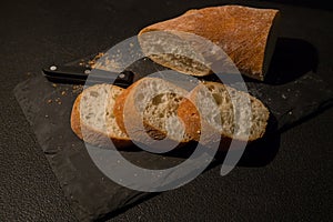 Slices of bread with crumbs and a knife on a black board background. View from above. World homemade