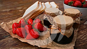 Slices of bread and delicious strawberry jam jar and fresh berries on wooden