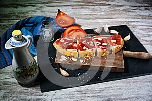 Slices of bread with ham, oil, tomato and garlic