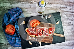Slices of bread with ham, oil, tomato and garlic