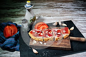 Slices of bread with ham, oil, tomato and garlic photo